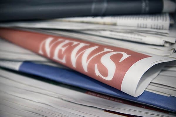 news papers stacked with one pulled out showing the word news