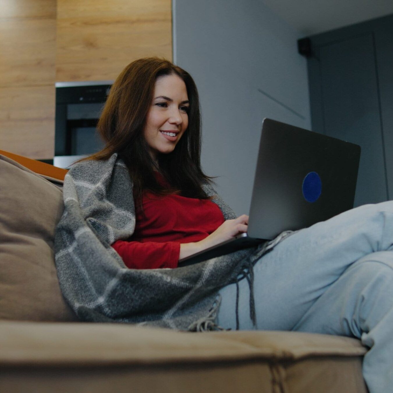 A,Woman,Sits,On,A,Cozy,Sofa,,Working,Intently,On