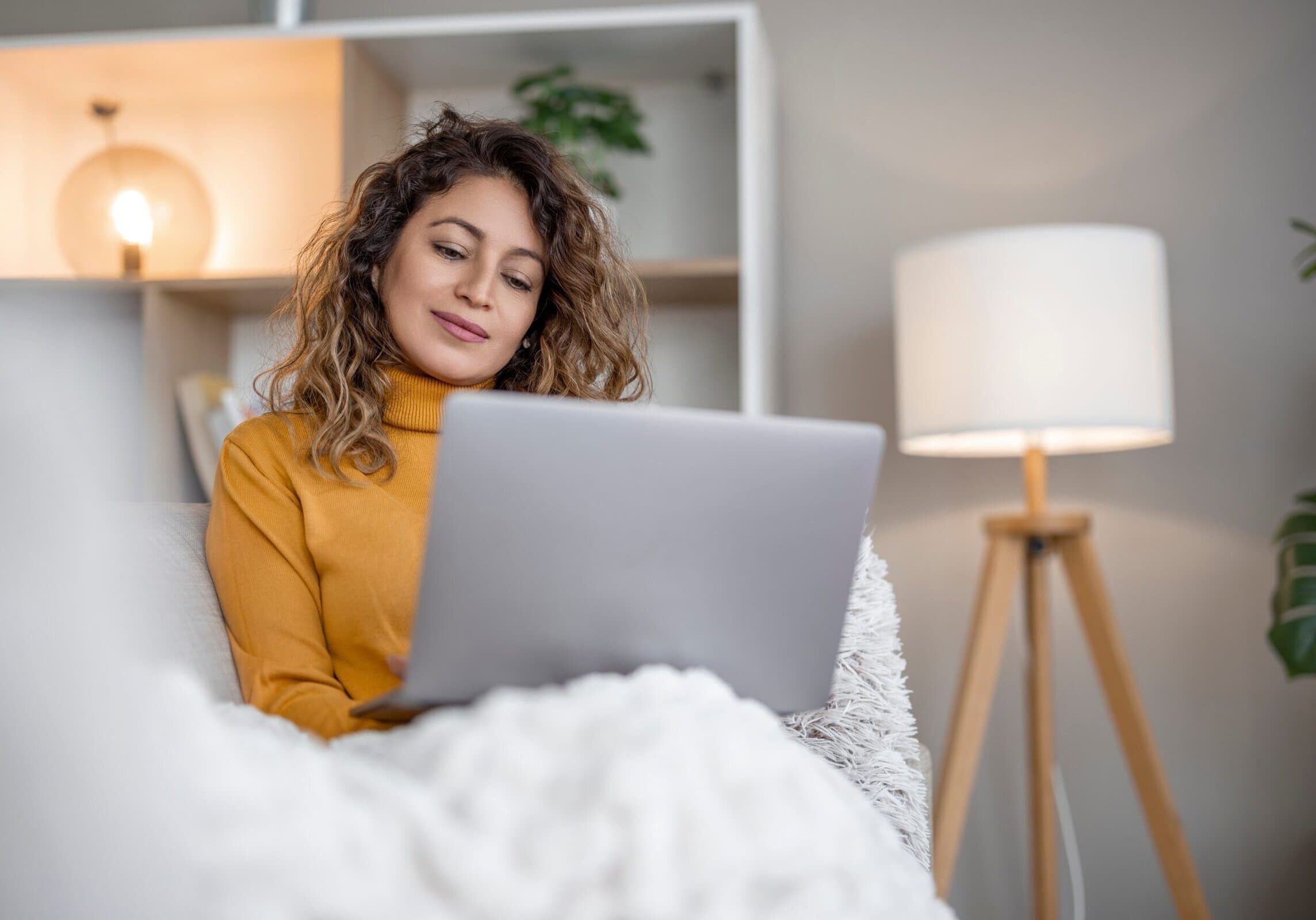 A,Woman,With,Curly,Hair,Sits,Comfortably,On,A,Soft