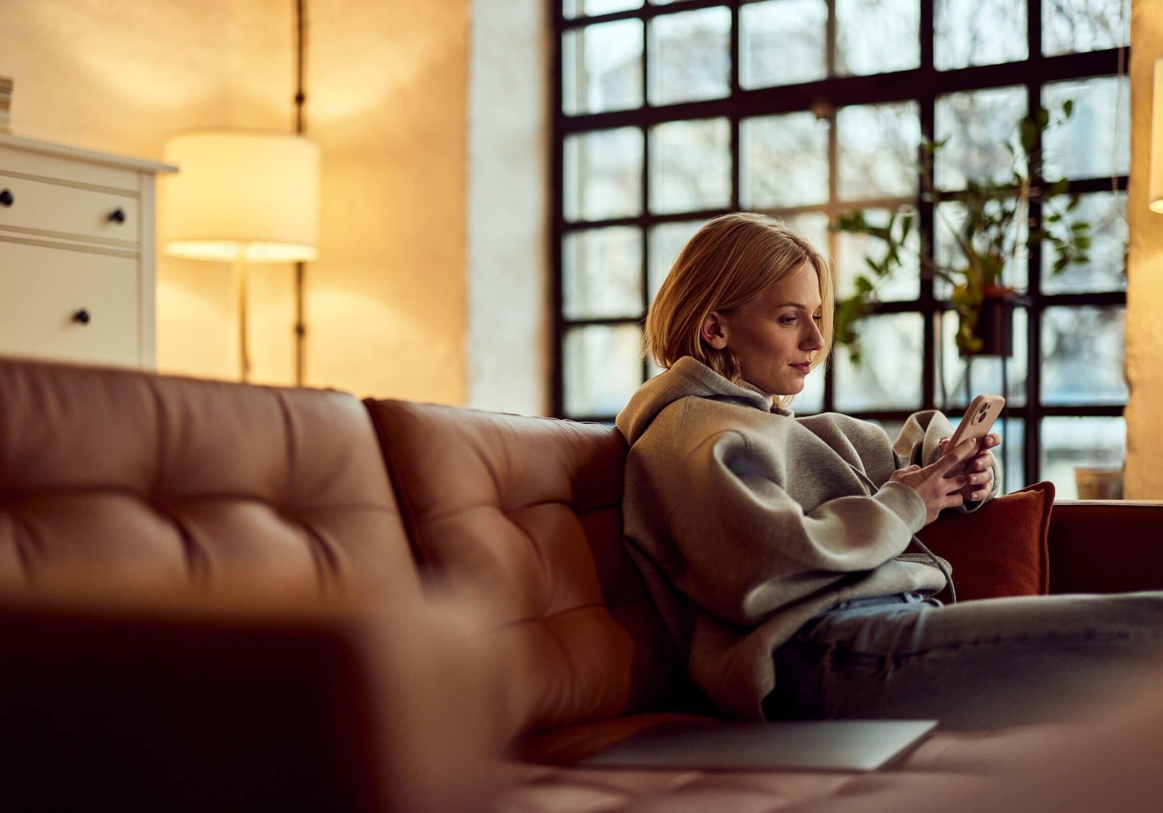 Young,Female,Sitting,Indoors,On,A,Comfy,Couch,Using,A