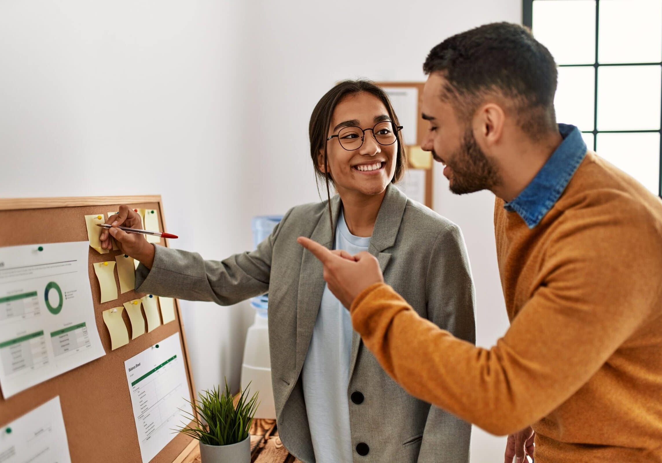Two,Business,Workers,Smiling,Happy,Writing,At,Corkboard,Reminder,At