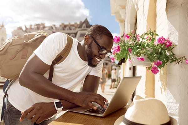 man in a Mediterranean setting working on a laptop as a digital nomad