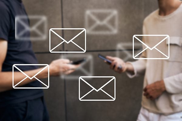 two people holding cellphones with an overlay of multiple email icons