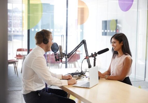 two people sitting across from eachother recording audio