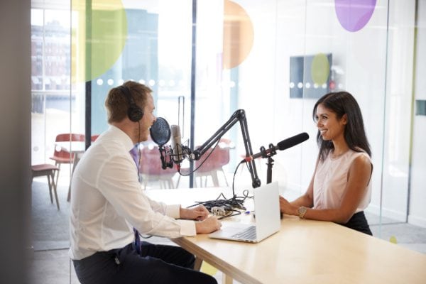 two people sitting across from eachother recording audio